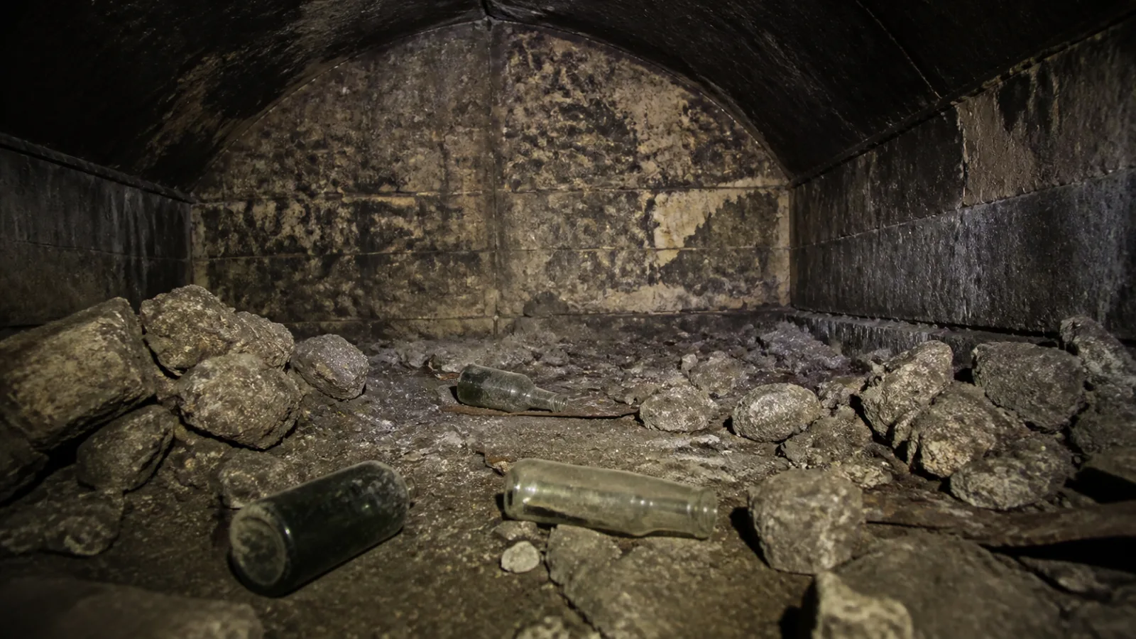 Close-up of an empty dusty vault interior containing only rubble and broken bottles
